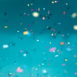 Colorful confetti falling down with a teal background