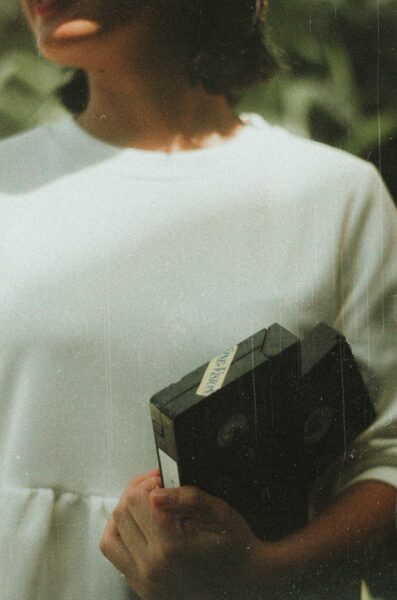 Woman with vintage VHS tapes evoking nostalgia and secrets