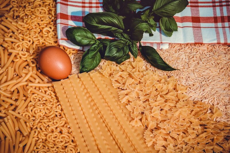 Various types of pasta including orzo in a grocery store.