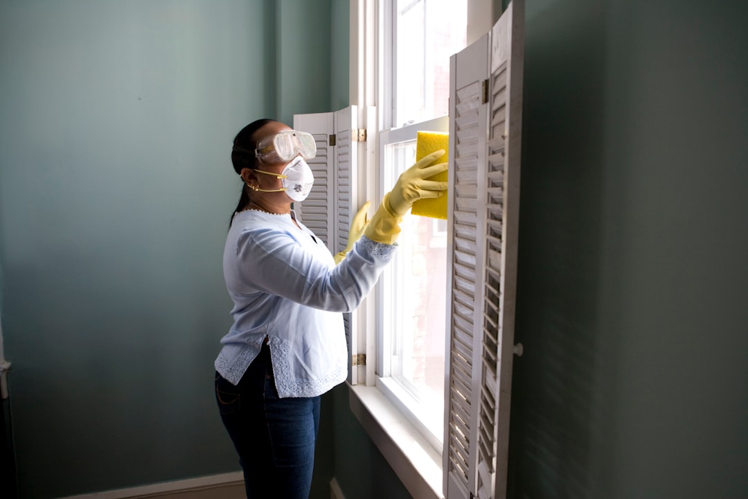 When renovating a home, you should use a damp sponge or cloth to clean dust collected on a window sill, as the dust may contain asbestos or lead-based paint. Home maintenance is an ongoing process for any homeowner, and here we see an African- American woman who’d taken a damp sponge to her window’s frame, in order to remove accumulated dust particulates. Note how the homeowner had donned a pair of waterproof gloves, a facemask, and a pair of goggles, prior to beginning this task. woman in white long sleeve shirt and blue denim jeans standing beside white wooden framed glass