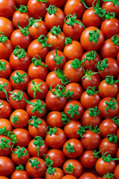 High-angle view of fresh, juicy cherry tomatoes with vibrant green stems, creating a natural pattern.