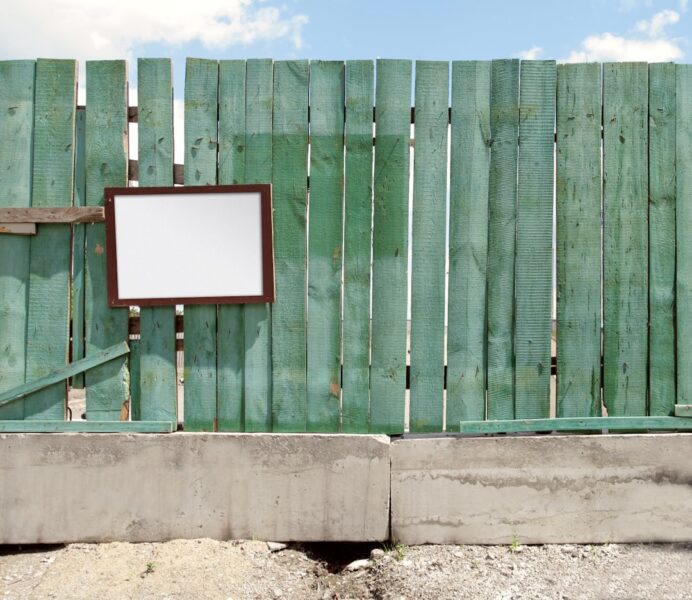 A wooden fence with a decorative mirror hanging on it.