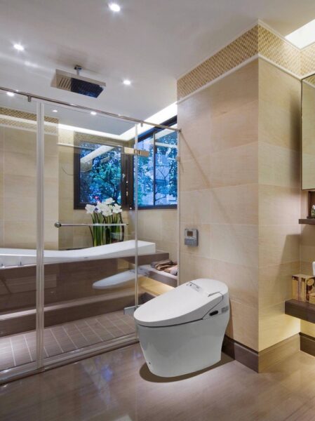 Contemporary beige luxury bathroom design with glass shower stall and smart bidet toilet.