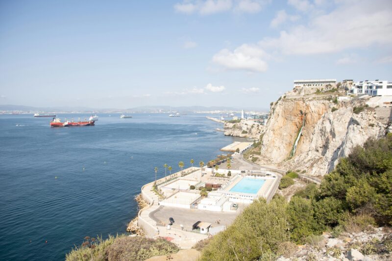 A breathtaking view of the coastline featuring cliffs, a resort, and calm sea waters.