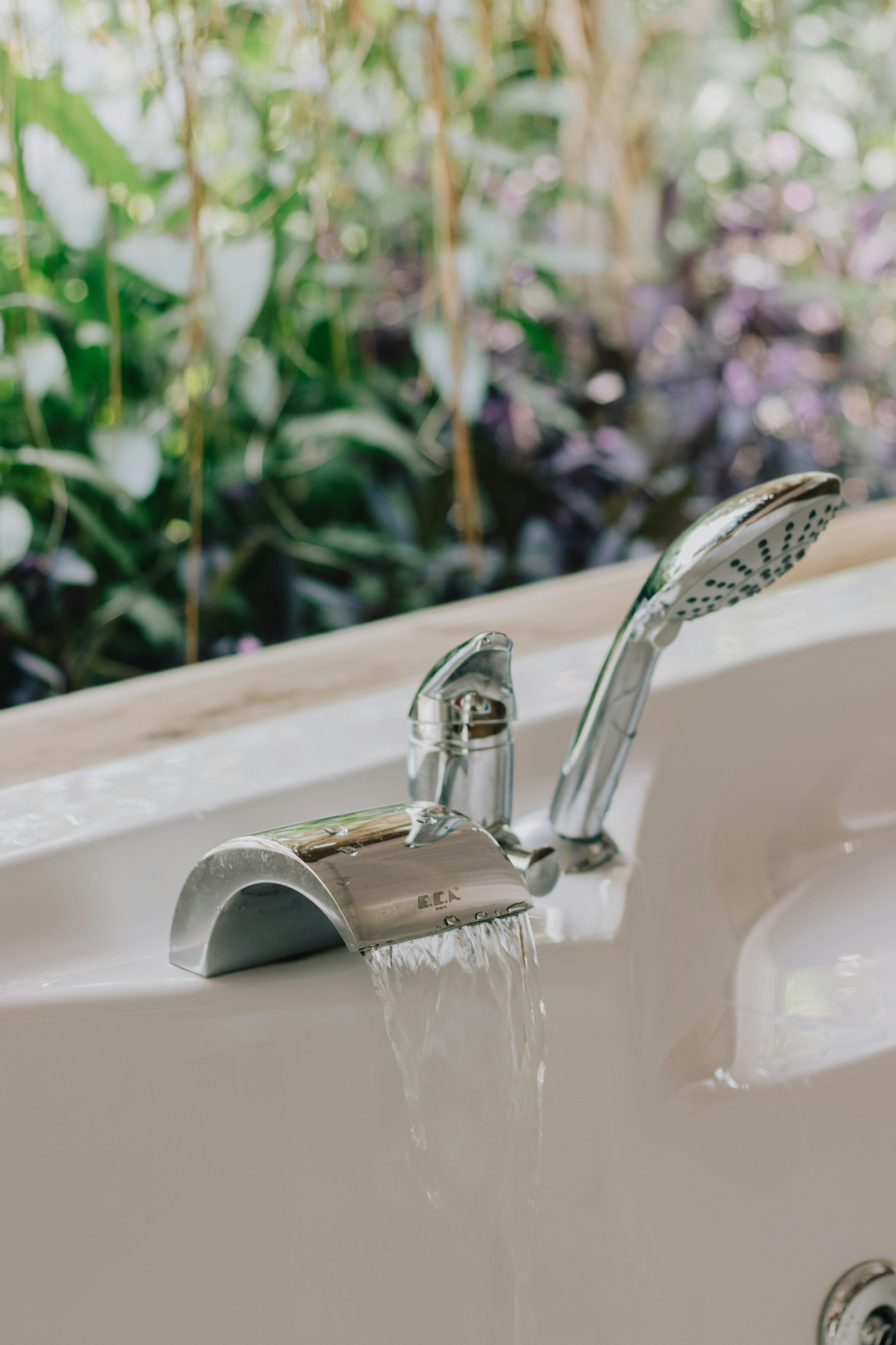 Elegant bathroom design featuring a modern bathtub faucet with scenic greenery visible through the window.