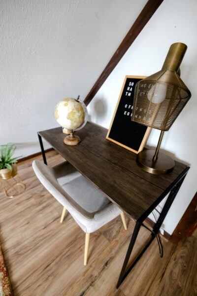 A stylish home office setup featuring a globe, lamp, and letter board on a wooden desk.