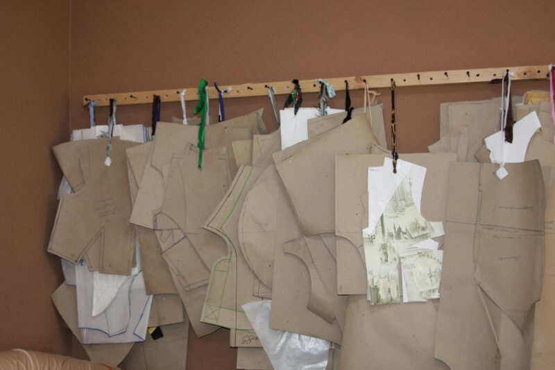Close-up of various sewing patterns hanging on a pegboard wall using strings.