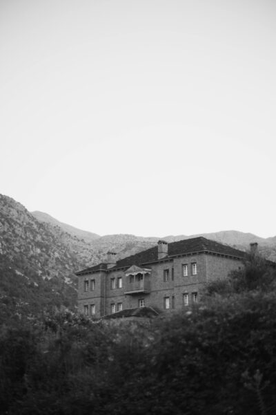 A tranquil black and white photo of a house nestled among misty mountains.