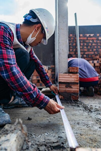 Construction worker using a measuring tape on an active building site in Hải Phòng.