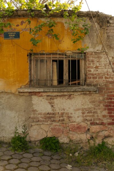 Rustic yellow wall with weathered barred window