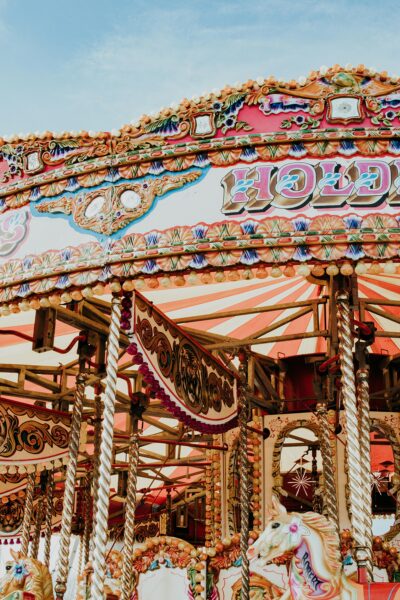 Vibrant and colorful carousel at an amusement park under a clear blue sky.