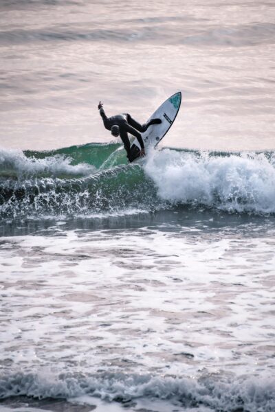 A surfer performs an impressive maneuver on ocean waves in Cambria, CA