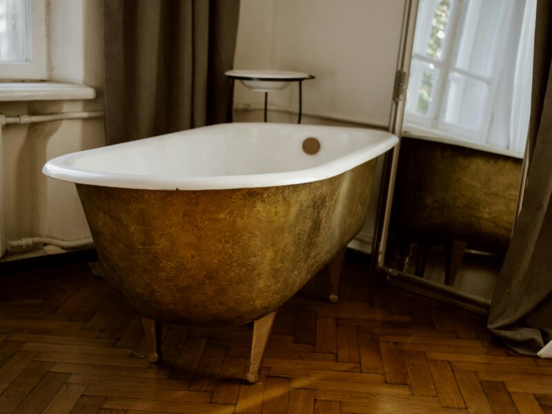 A stylish vintage-style bathroom with a gold bathtub and elegant decor.