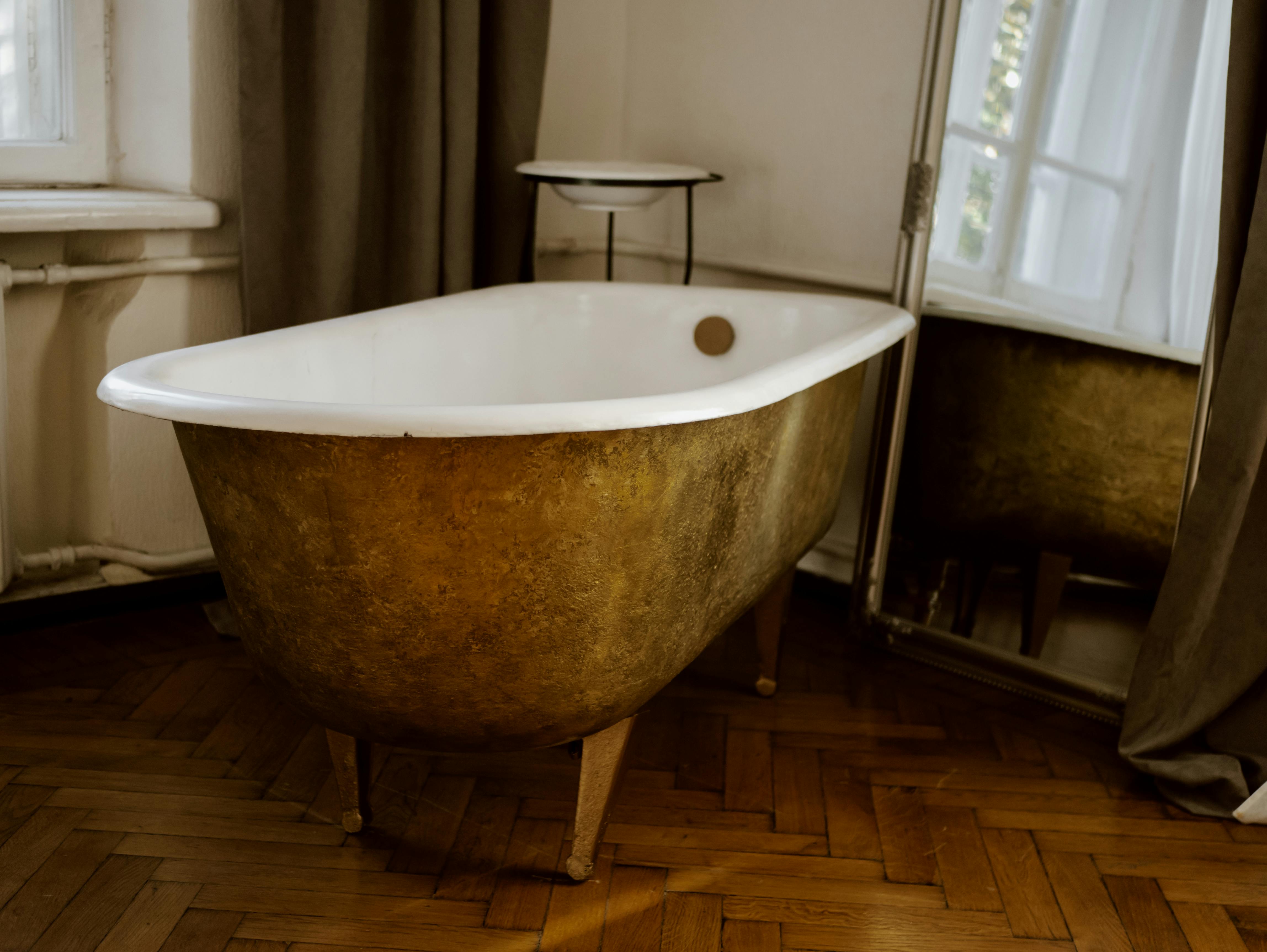 A stylish vintage-style bathroom with a gold bathtub and elegant decor.
