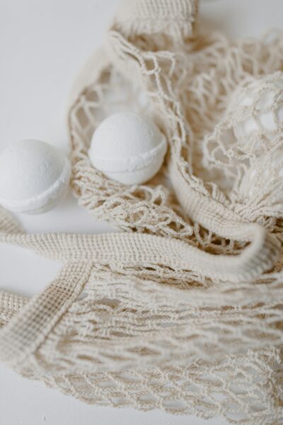 Minimalist photo of white bath bombs in a textured mesh bag, highlighting eco-friendly spa products.