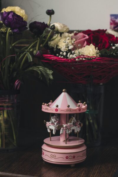 A beautiful floral display featuring a small pink carousel and vibrant blooms for interior decor.