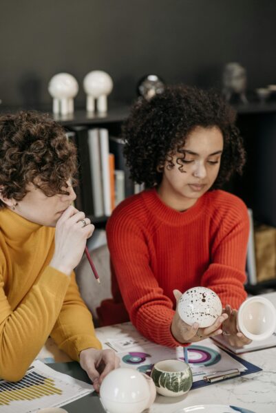 Two designers discussing ceramic prototypes at a modern office table.