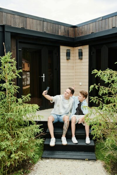 Two boys taking a selfie on garden steps in front of a modern house