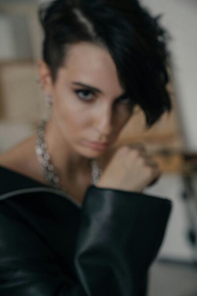 Blurry portrait of a stylish woman in a leather jacket with short brunette hair.