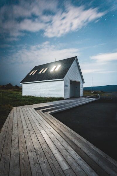 A serene white house with a slanted roof by a wooden boardwalk under a twilight sky