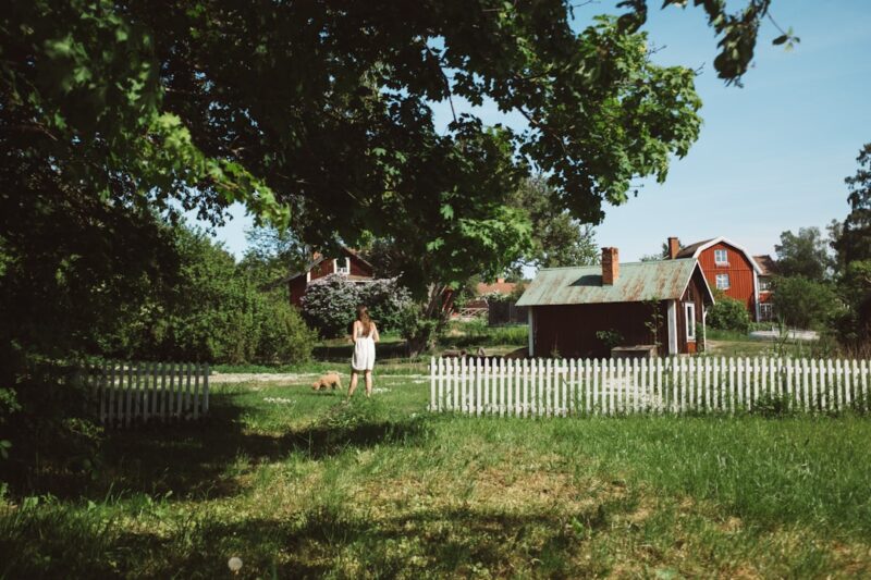 Woman standing beside dog in green lawn.
