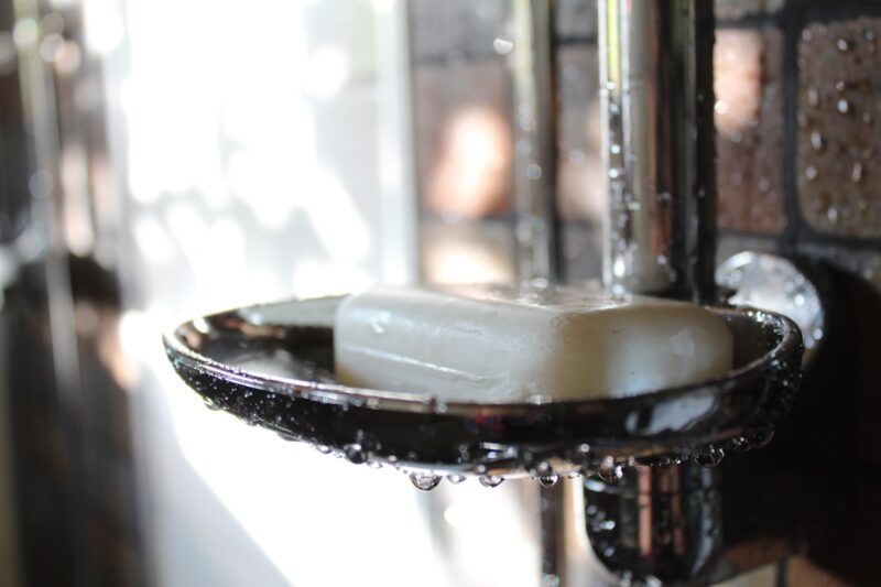 Soap resting on a soap holder in a wet bathroom setting.