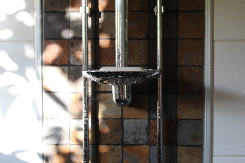 A bathroom with a brick wall and a shower head.