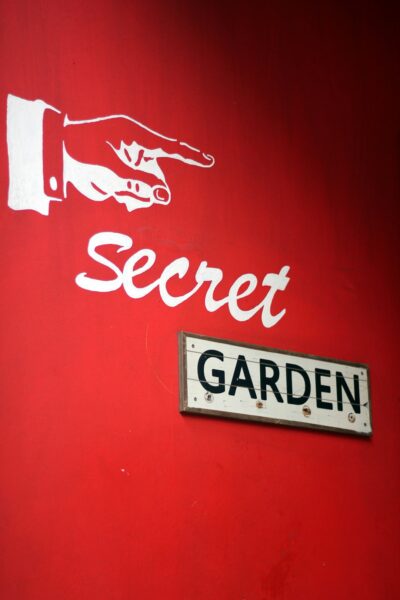 A sign on the side of a building that says secret garden.