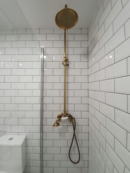 Gold shower head on white ceramic bathtub.