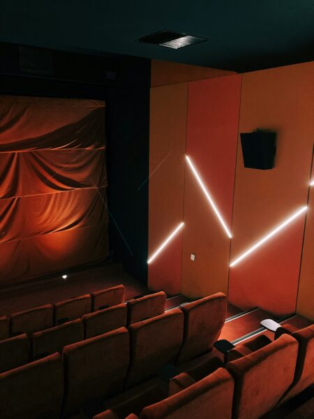 A theater with a row of seats and a projector screen