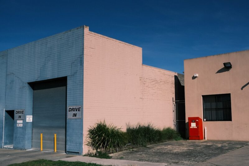 A pink building with a blue door and a red door.