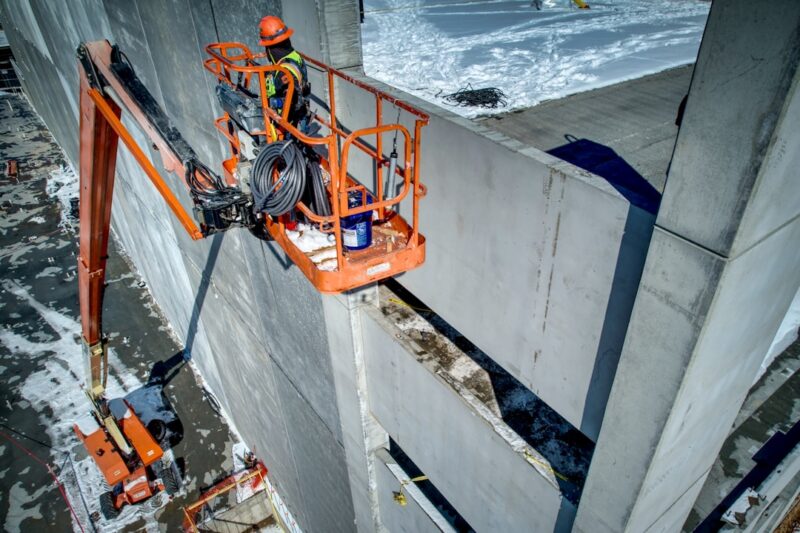 A construction worker is working on the side of a building.