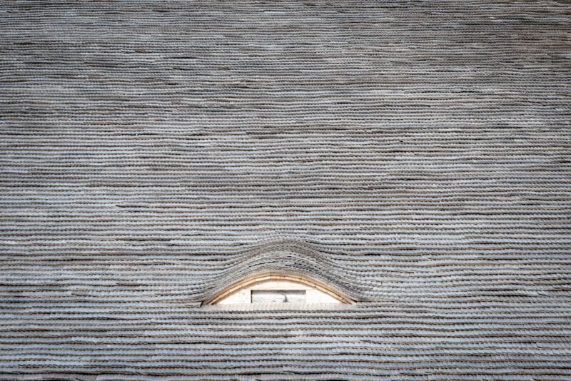 Eyebrow dormer window in a wooden shingle roof photographed in the Swiss Jura.