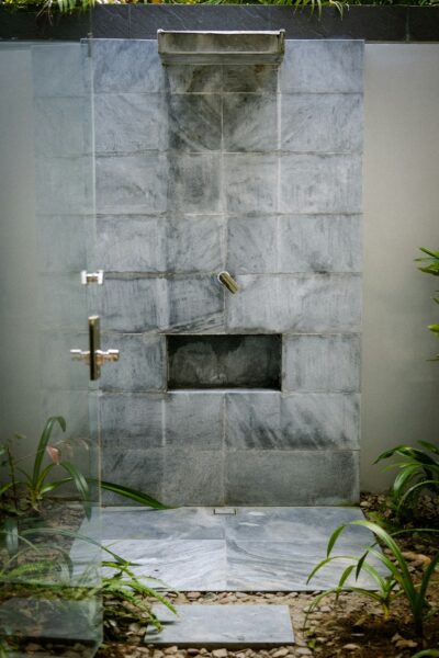 A walk in shower sitting next to a lush green forest