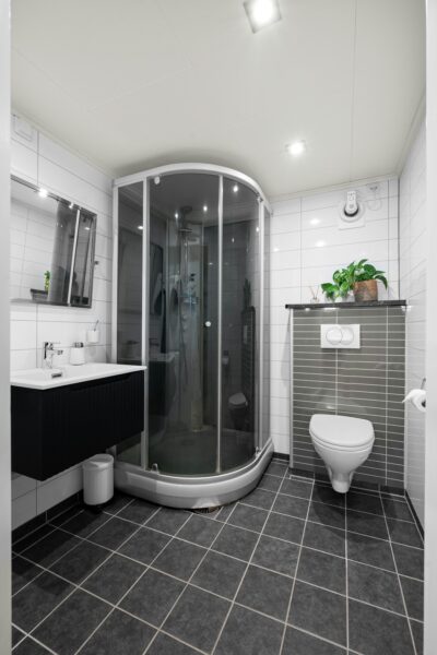 A bathroom with a toilet, shower, and sink.