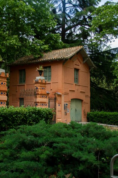 An orange house with a green door surrounded by trees.