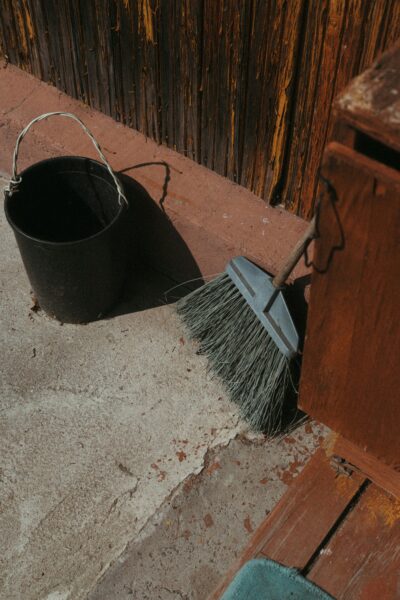 A broom and bucket sitting on the side of a building.
