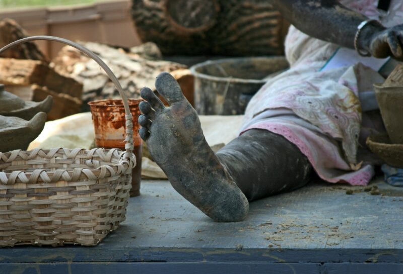 A person sitting on the ground next to a basket.