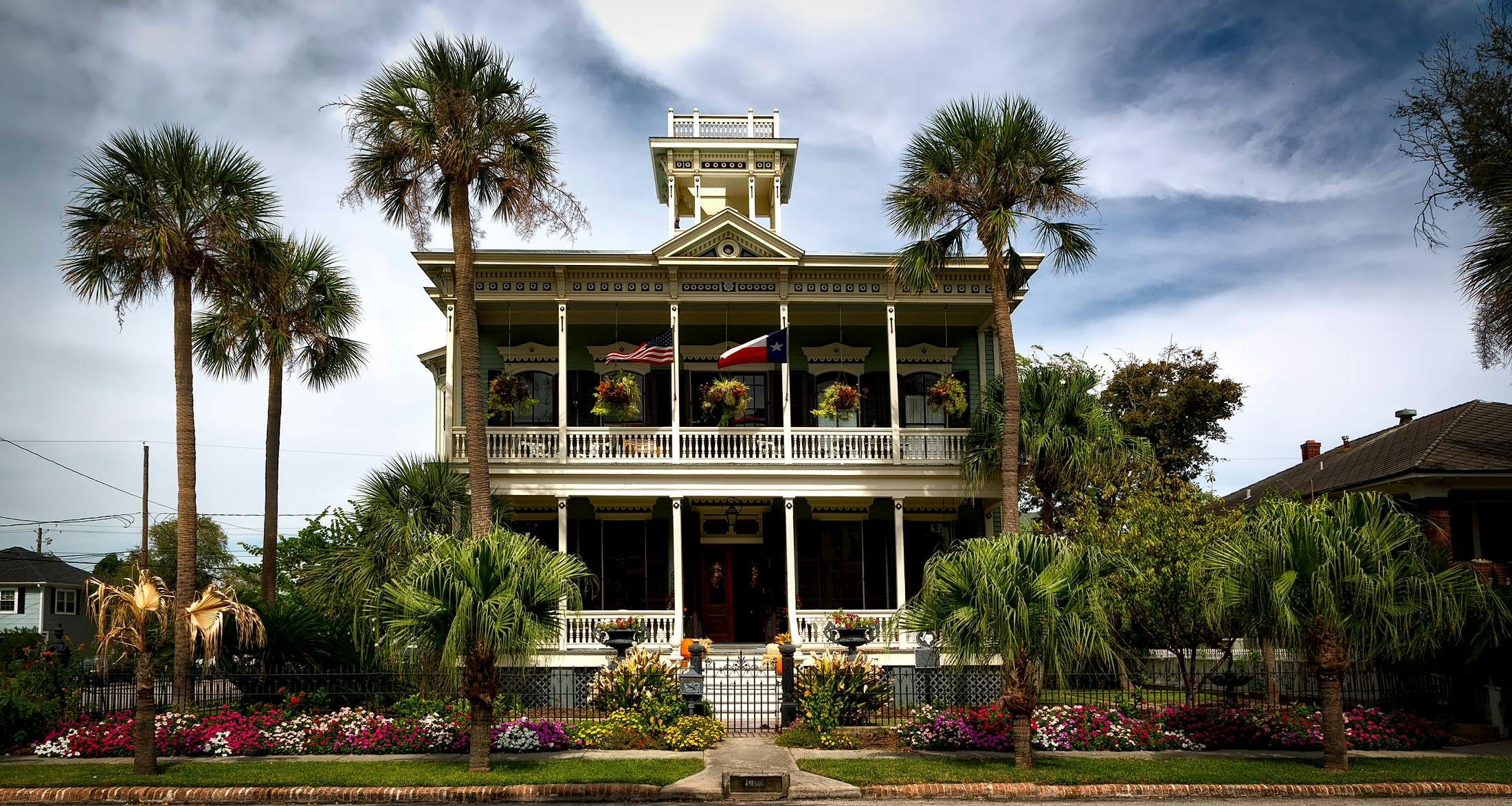 Stunning view of a historic mansion with lush gardens and palm trees in Galveston, Texas.