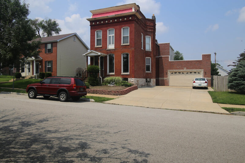 The image shows an open-space garage addition seamlessly blending from the main building facade.