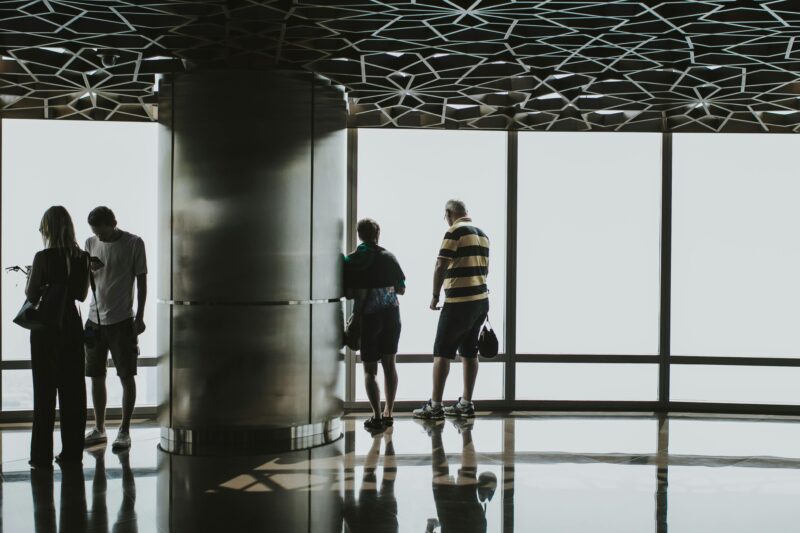 Four people observing a panoramic view from a modern high-rise in Dubai.