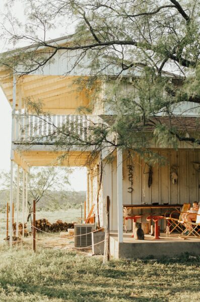 A charming rustic ranch house with a wooden porch surrounded by trees under daylight.