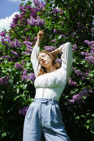 A woman enjoying springtime surrounded by blooming lilacs.