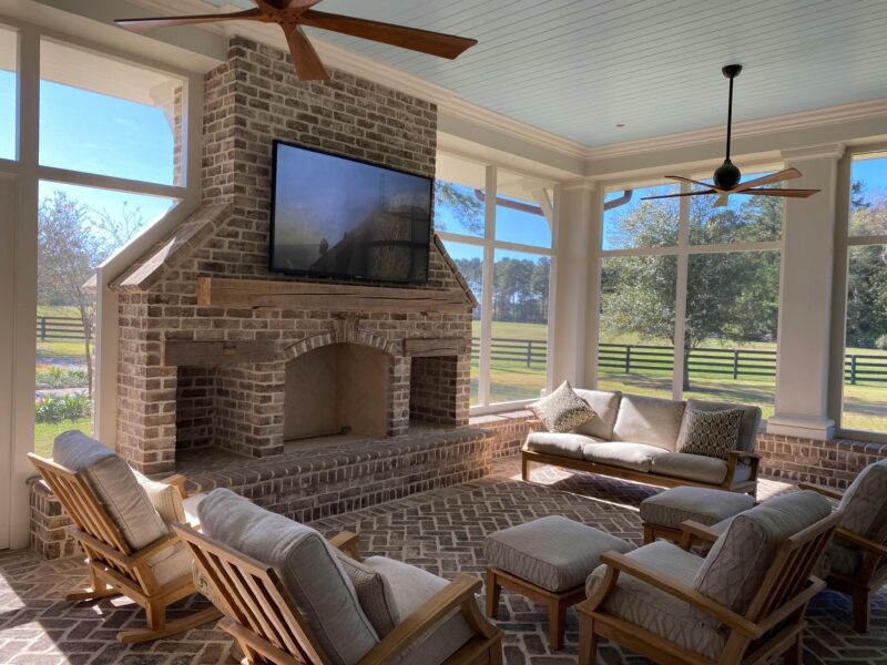 Beautiful sunroom featuring a brick fireplace, wooden furniture, and expansive windows with a scenic view.