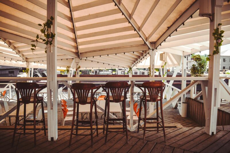 Elegant outdoor cafe with wooden furniture and decor, offering a cozy and stylish atmosphere.