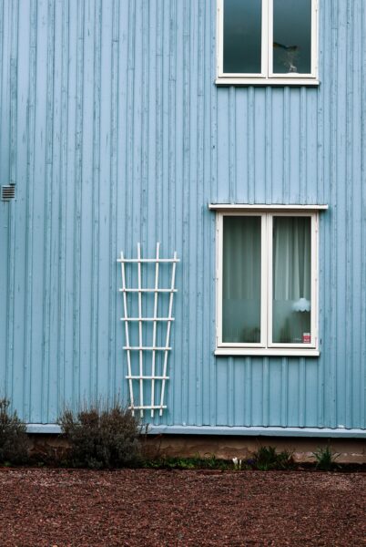 Exterior of a blue wooden house with a trellis