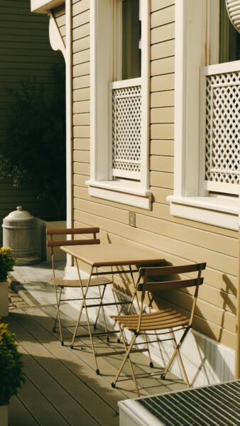 Charming porch scene with wooden table and chairs, perfect for relaxation.