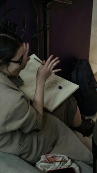 Woman sketching in a cozy, dimly lit room. Artistic and contemplative atmosphere.