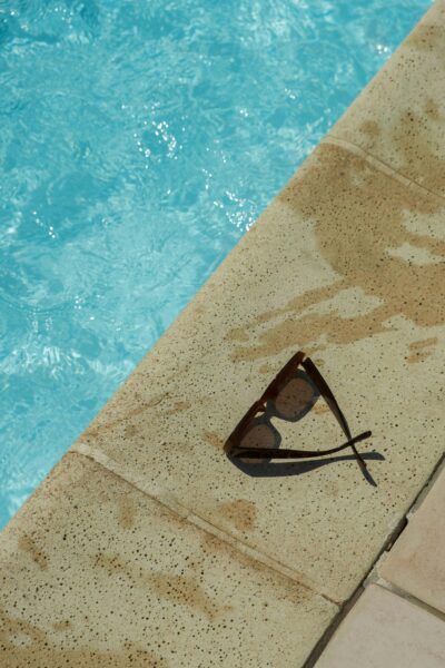 Close-up of sunglasses on a modern stamped concrete pool deck