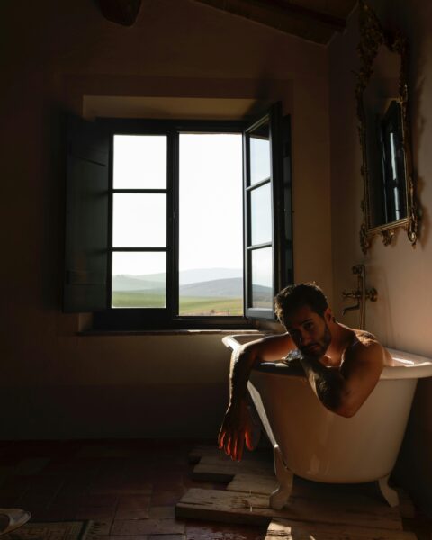Man enjoying a serene bath with a view of Tuscany. Beautiful lighting and atmosphere.